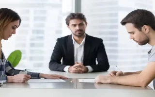 مشاوره حقوقی حضوری| وکیلی در دفتر وکالت که زن و مردی در کنار او برای مشاوره حضوری آمده اند