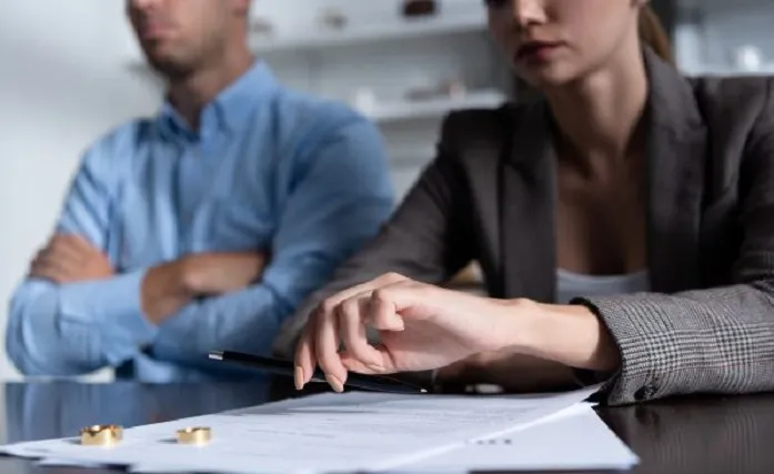 طلاق از طرف مرد؛ چه موانع و چالش_هایی وجود دارد ـ صلح آفرین| مرد و زنی در اتاقی در حال مشاوره و روی میز برگه و حلقه های ان ها وجود دارد